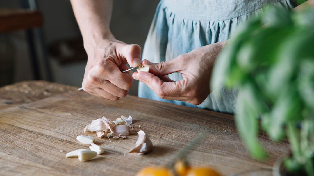 Frau schält Knoblauch